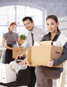 Happy businesspeople moving to new office, packing boxes, smilin